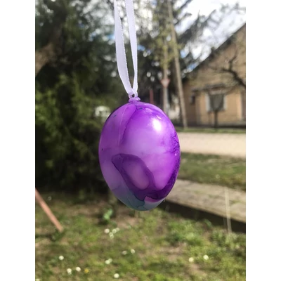 Márványmintás tojás fehér szalagra fűzve, lila és kék színekben.