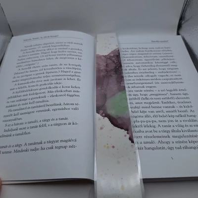 Téglalap alakú könyvjelző, fehér alapon középen sötétlila-zöld folttal, körülötte halvány lila pöttyökkel.