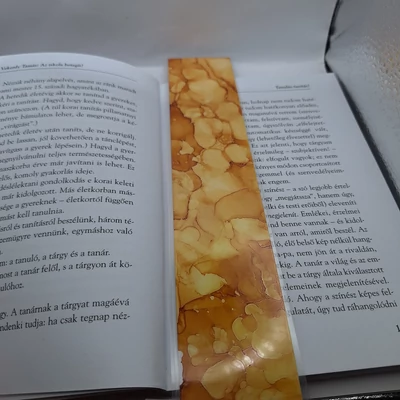 Téglalap alakú könyvjelző, sárga alap barnás részekkel, gömbös mintákkal.