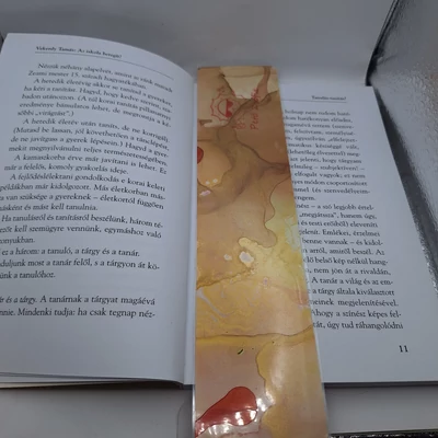 Téglalap alakú könyvjelző barna és arany mintával, egy vörös folttal. Rajta Zsófi logója: piros napszemüveges napocska kólát iszik, alatta Pető Zsófia felirat.
