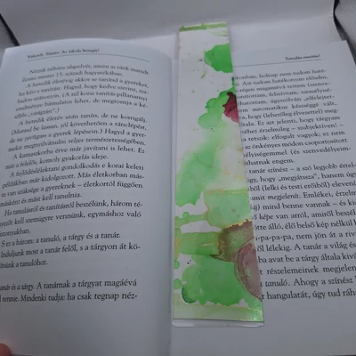 Téglalap alakú könyvjelző világoszöld mintával, a szélén bordóval.