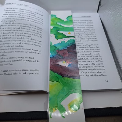 Téglalap alakú könyvjelző, fehér alapon zöld foltok sárga széllel és lila folt kék széllel.