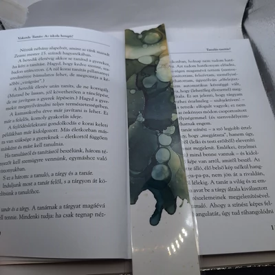Téglalap alakú könyvjelző fehér alapon fekete és más sötét színekből álló, buborékos mintával.