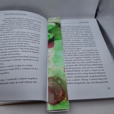 Téglalap alakú könyvjelző világoszöld alappal, rajta vörös gömbökkel.