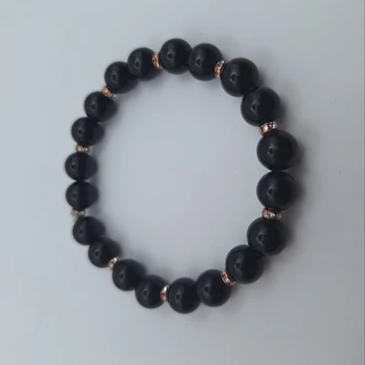 8 miliméteres, gömbalakú fekete gyöngyökből fűzött karkötő. A szemek között kétszemenként apró, strasszokkal díszített rosegold színű köztesek.
